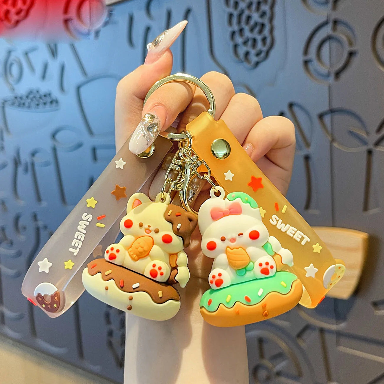 Hand holding a keychain with kawaii cartoon character design against a decorative background