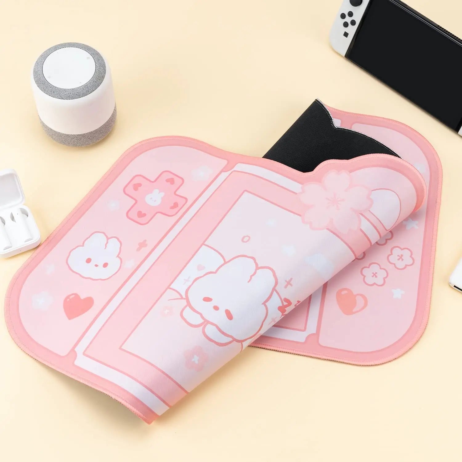 Pink Kawaii cartoon-themed mouse pad on a light yellow surface with electronic devices.
