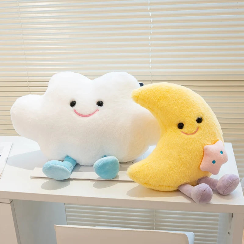 Two kawaii plush toys shaped like a cloud and a moon on a white surface with a window blind background.
