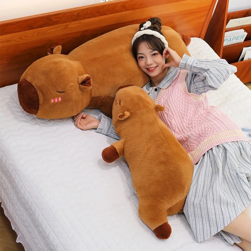 Person lying on a bed with large brown kawaii plush toys shaped like animals