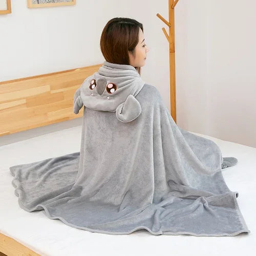 Person wearing a gray kawaii animal-shaped hooded blanket in a room with wooden furniture.