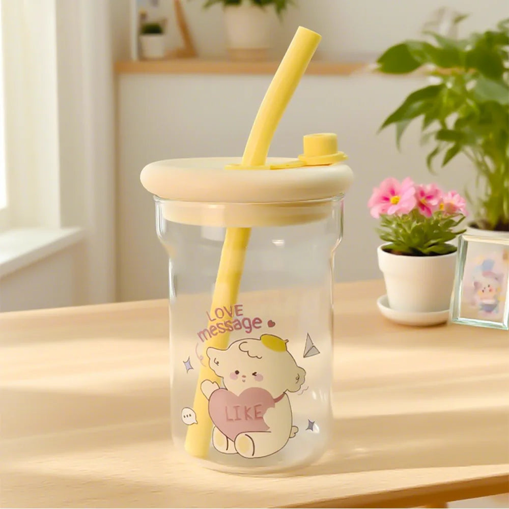 Glass tumbler with a Kawaii cartoon design and yellow straw on a wooden table.