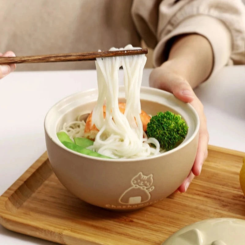 Person using chopsticks to lift noodles from a kawaii ramen bowl.