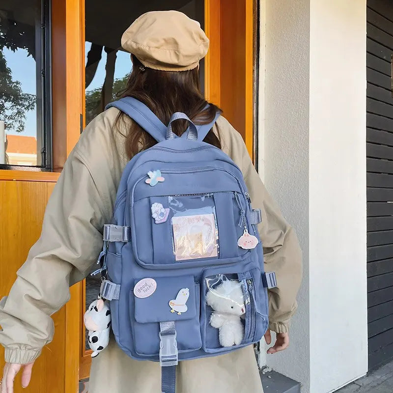 Person wearing a Kawaii blue backpack with decorative items, standing outside a building.