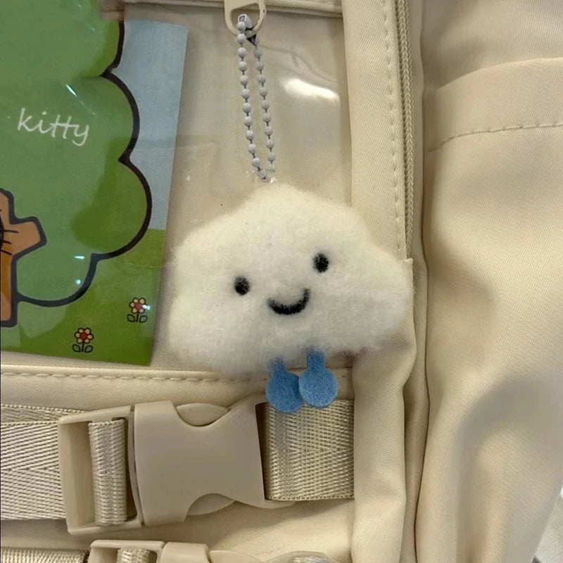 Plush cloud kawaii keychain attached to a beige bag with a 'kitty' card in the background.