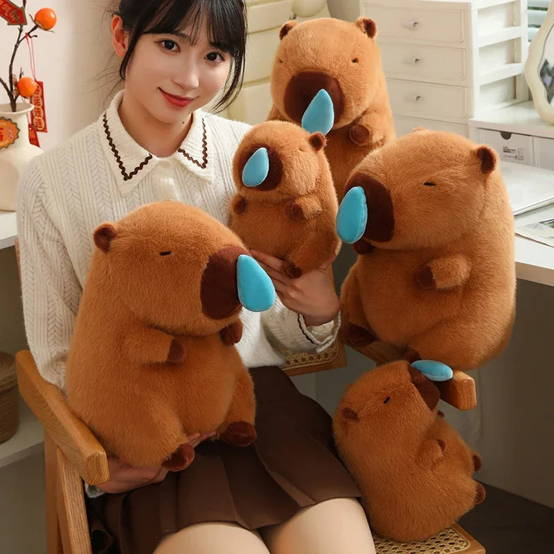 Person holding kawaii plush beavers with blue ears in a kitchen setting