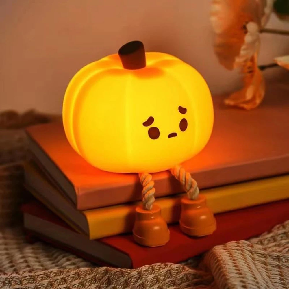 Cute kawaii pumpkin-shaped night light with a face on a stack of books.
