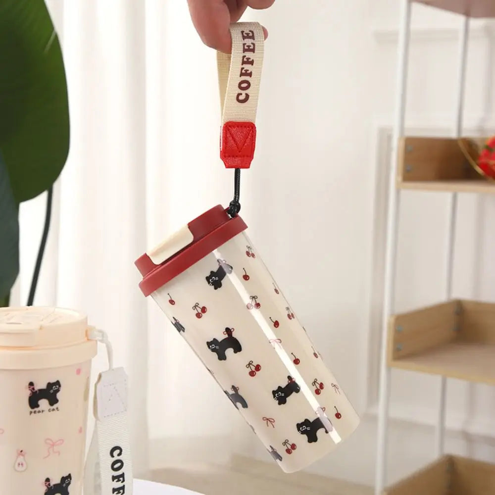 Clear tumbler with black dog Kawaii pattern and red lid held by a hand against a neutral background