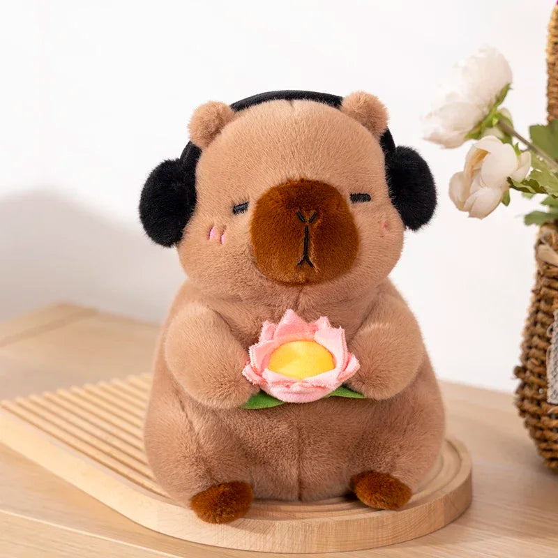 Kawaii plush toy resembling a bear with a flower and black headphones on a wooden surface.