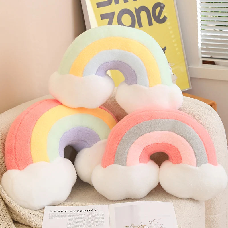 Set of rainbow-shaped kawaii cushions on a surface with a 'Happy Everyday' book in the background.