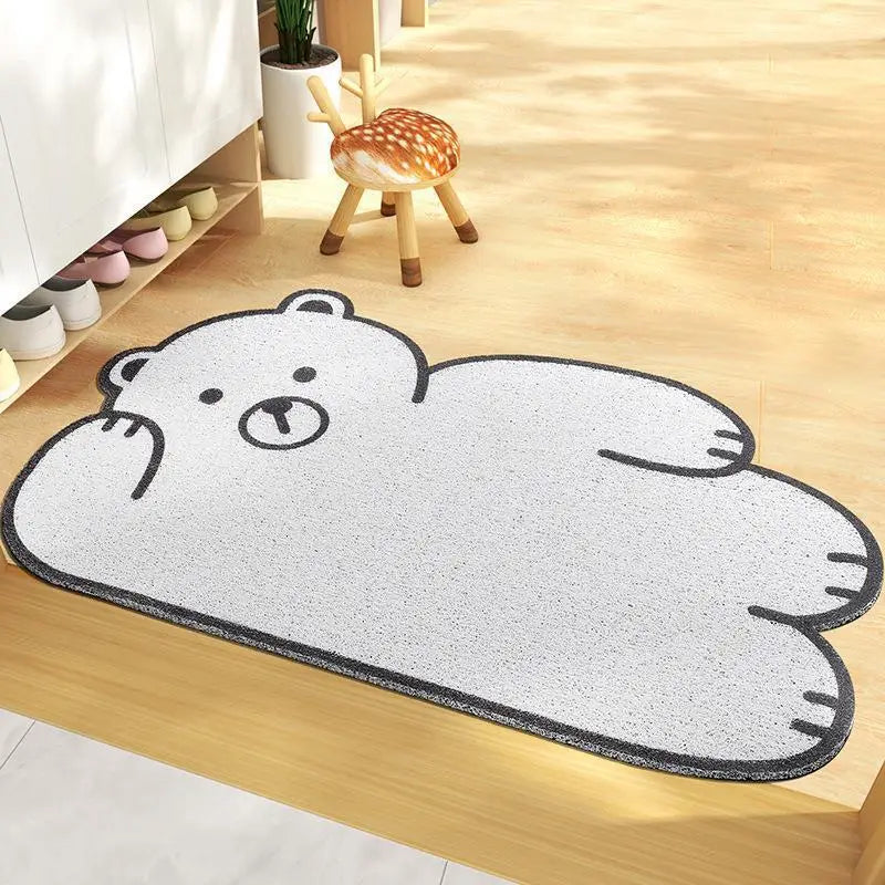 Kawaii bear-shaped rug on a wooden floor with a small stool and shoes in the background.