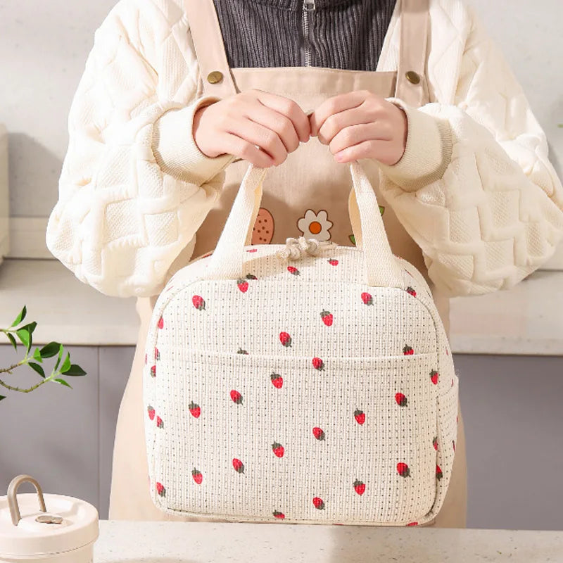 Person holding a woven bag with kawaii strawberry pattern in a kitchen setting