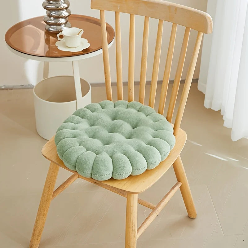 Green kawaii cushion on a wooden chair with a small table and decor items in the background.