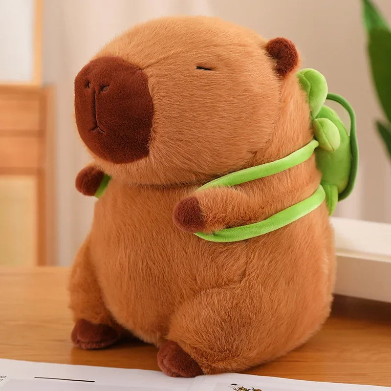 Plush toy resembling a kawaii capybara with a green leaf on a wooden surface