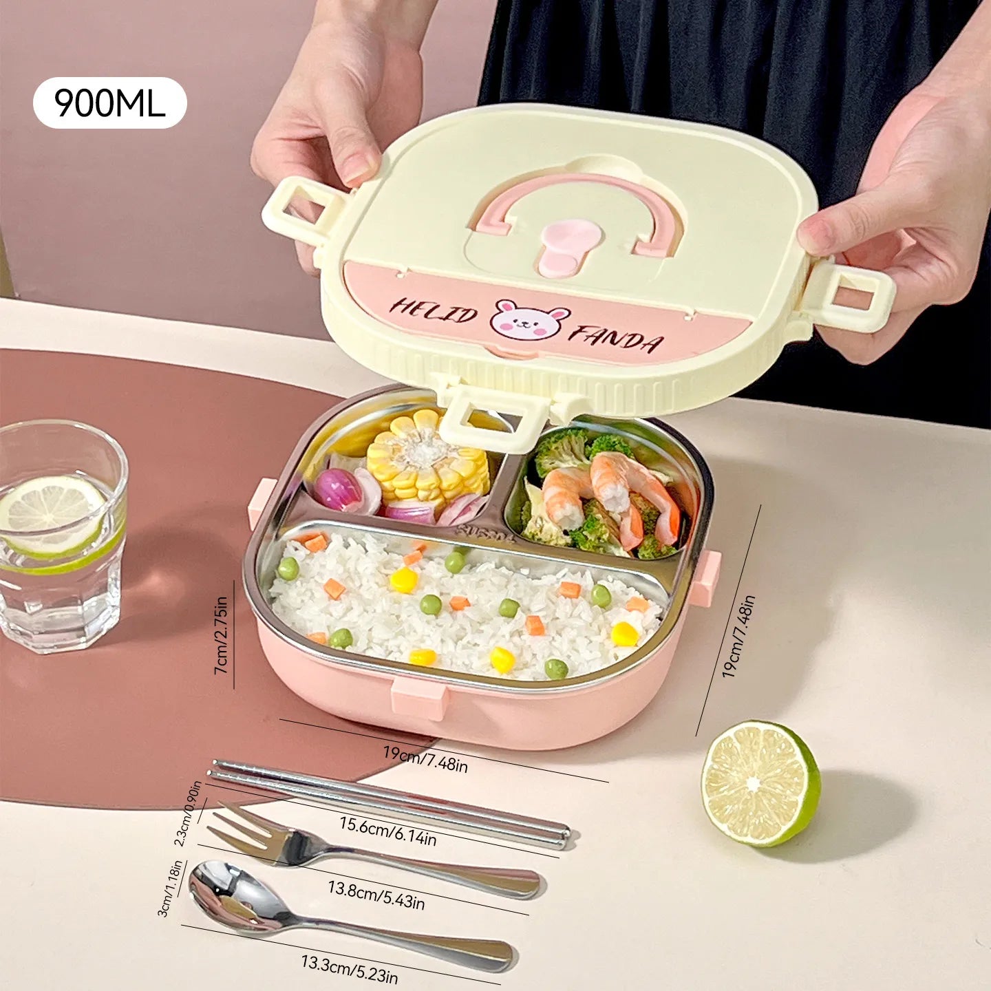 Pink and beige kawaii lunch box with compartments, utensils, and a glass of water on a pink surface.