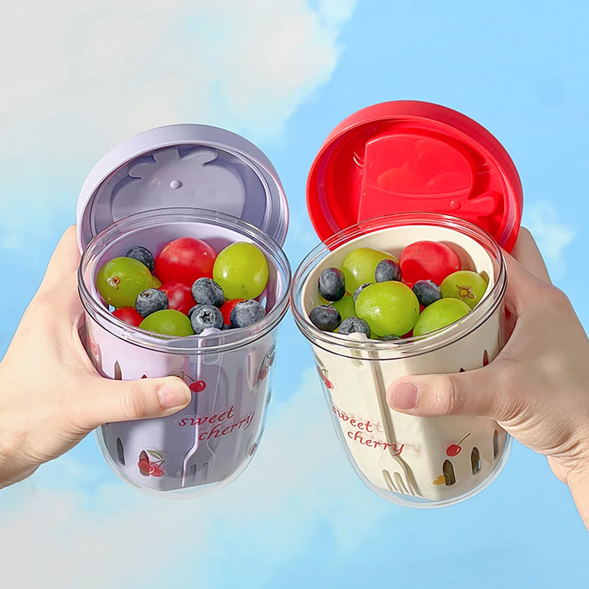 Two Kawaii-style containers with lids filled with fruits against a blue background