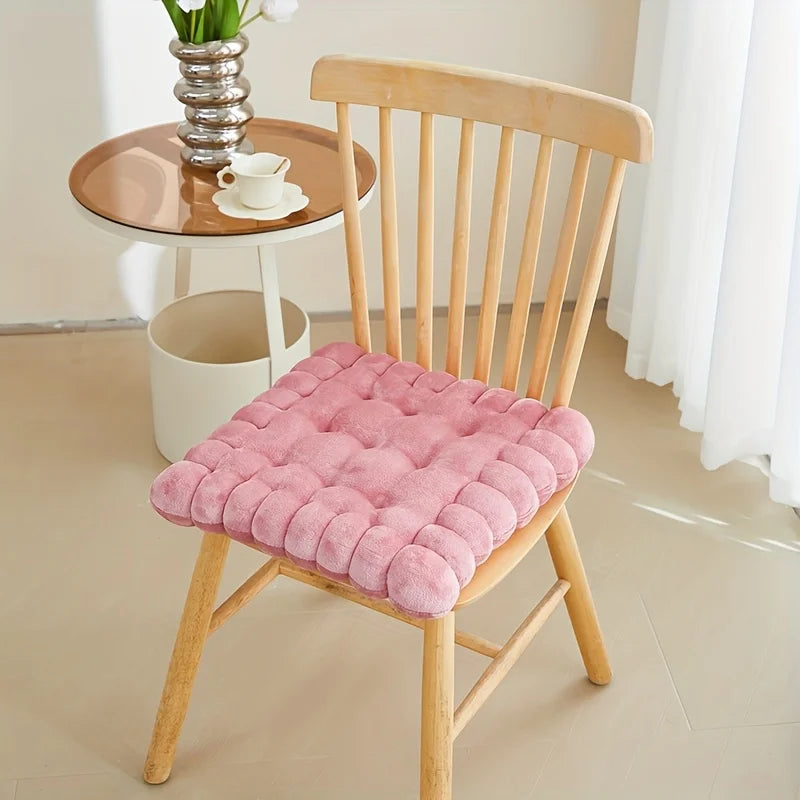 Pink kawaii cushion on a wooden chair with a small table and decor in the background