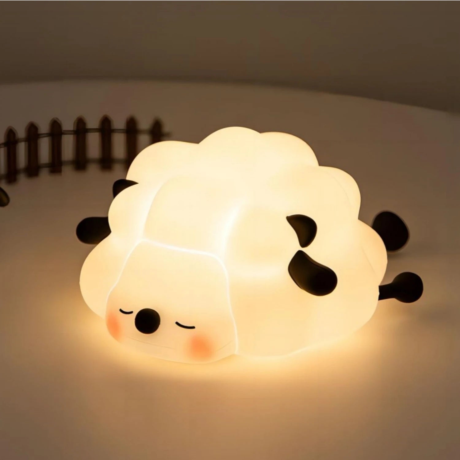 Cute sheep-shaped kawaii night light emitting a warm glow on a soft surface.