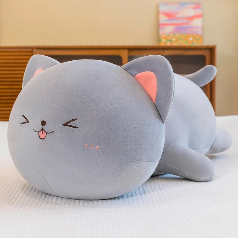 Gray kawaii cat-shaped plush toy on a bed with a blurred background