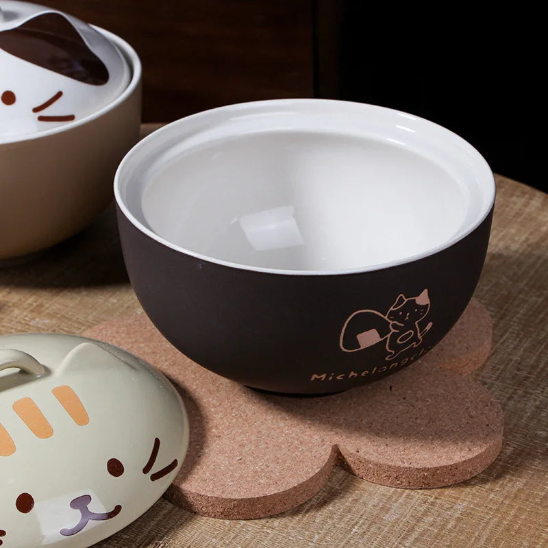 Ceramic bowls with kawaii cat designs on a wooden surface