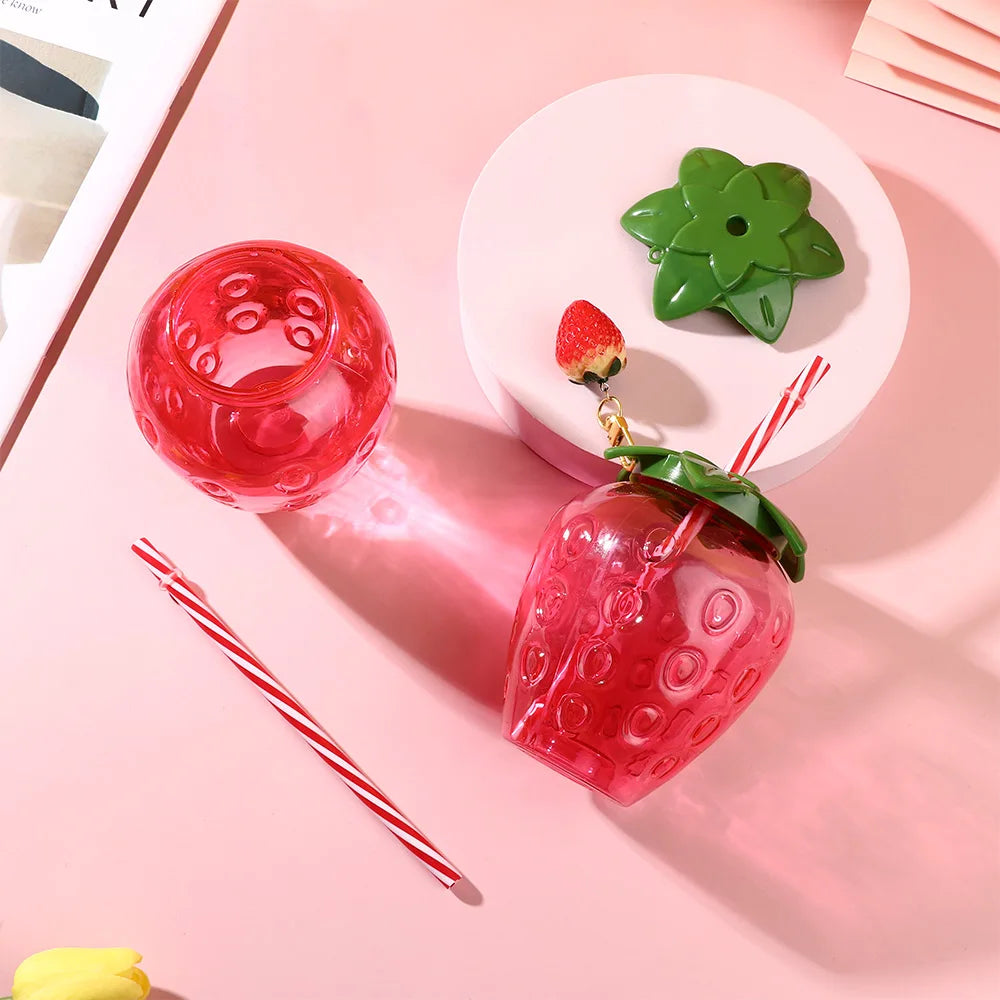 Kawaii strawberry-shaped drink container with a lid on a pink background