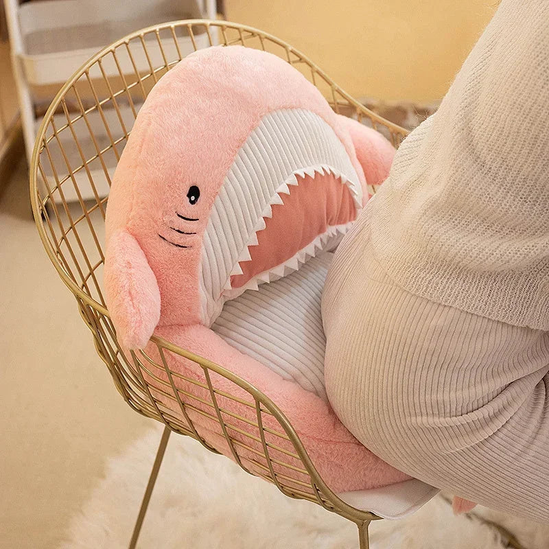 Pink shark-shaped kawaii cushion on a gold wire chair with a blurred background