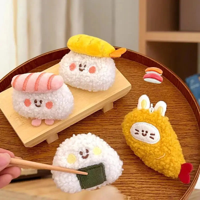 Plush toys resembling kawaii sushi on a wooden tray with a hand holding chopsticks.