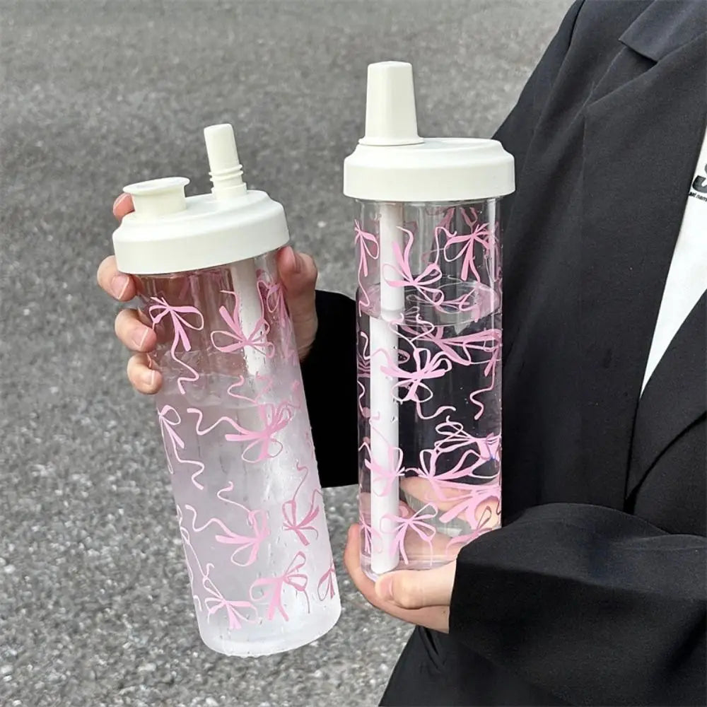 Two Kawaii clear water bottles with pink bow designs held by a person.