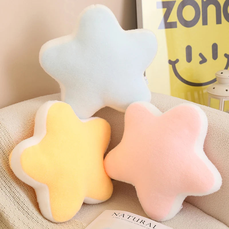 Star-shaped kawaii cushions in white, yellow, and pink on a beige surface with a Zoneparc bag in the background.