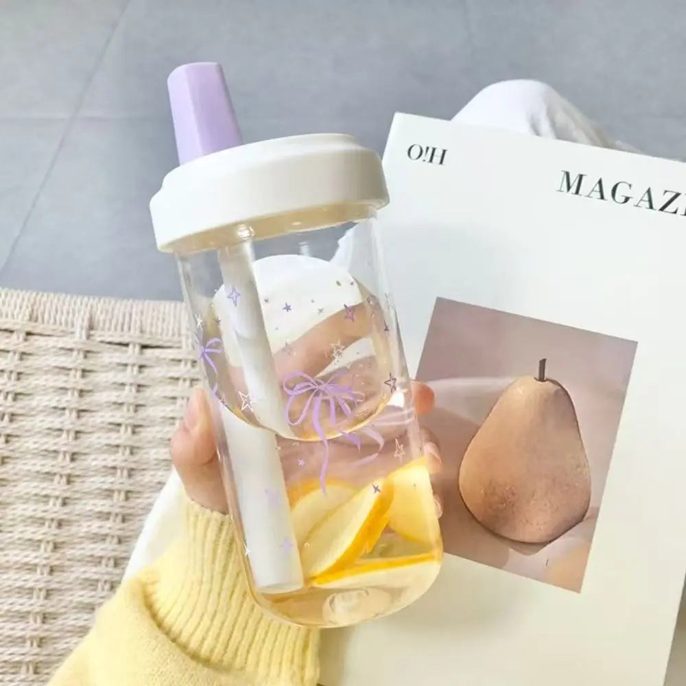 Kawaii clear tumbler with purple lid held by a person, with a magazine featuring a pear in the background.