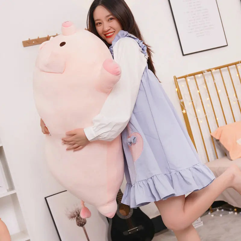 Woman holding a large pink kawaii plush toy in a room with a white wall and decorative items.