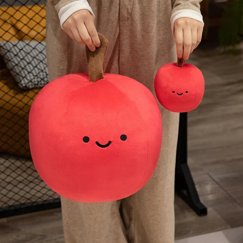 Person holding two kawaii plush apple toys with smiling faces.
