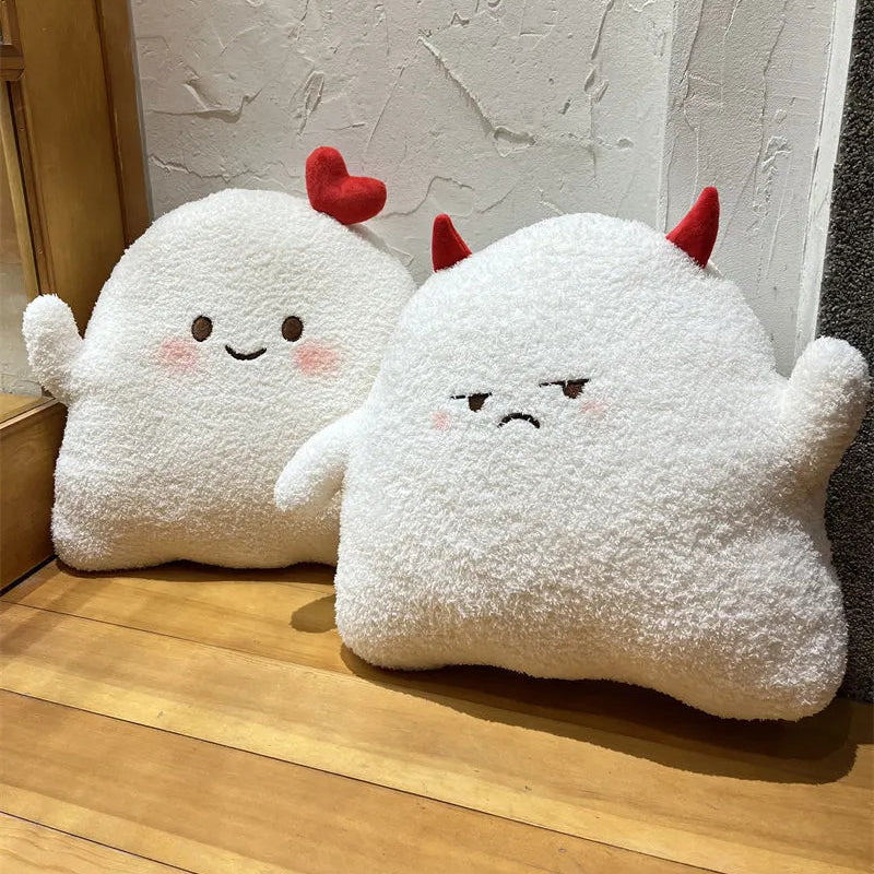Two kawaii plush toys resembling ghosts with red horns on a wooden floor.