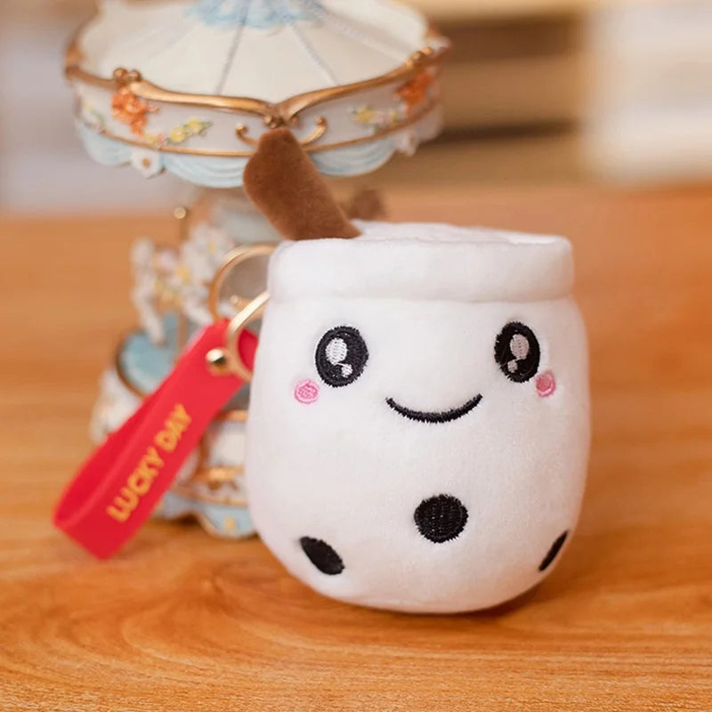 Plush keychain shaped like a kawaii cartoon milkshake with a smiling face on a wooden surface.