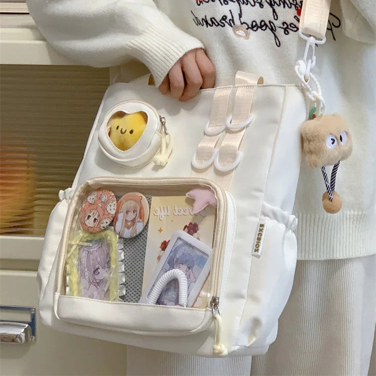 Person holding a white Kawaii backpack with cartoon character designs, wearing a matching sweater.