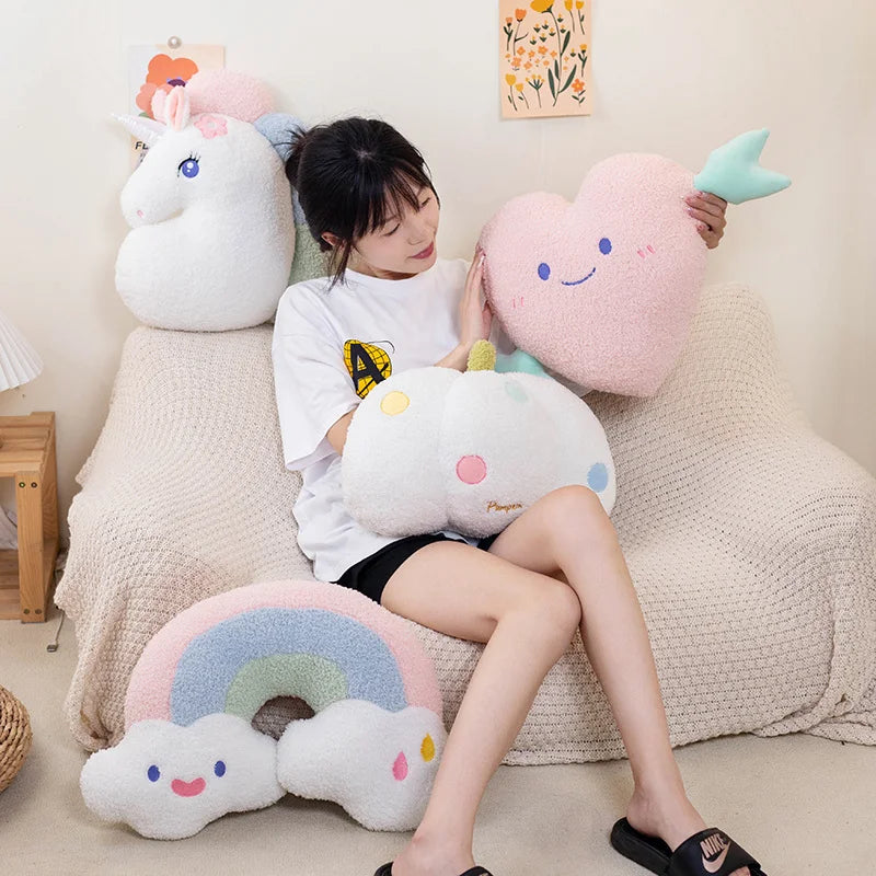 Person sitting on a couch with large, colorful cloud-shaped kawaii cushions.
