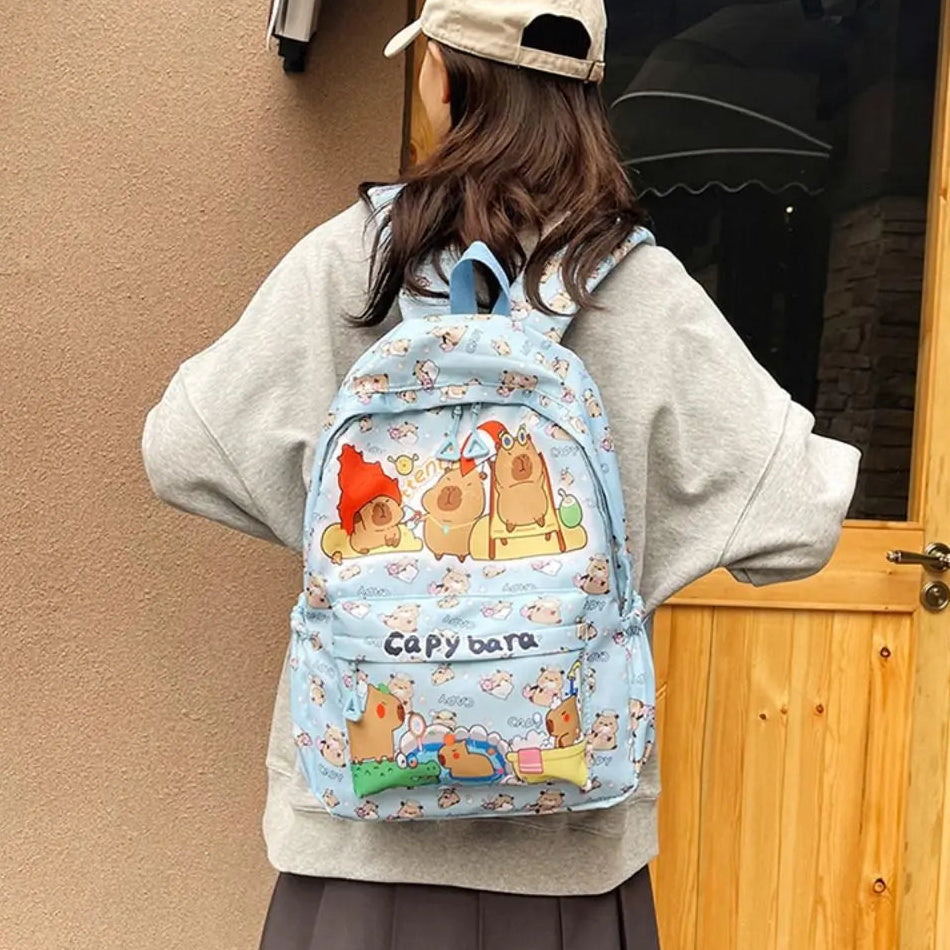 Person wearing a blue Kawaii backpack with cartoon designs, standing in front of a wooden door.