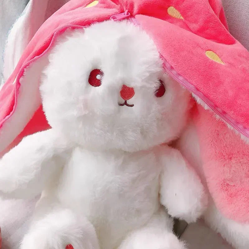 White plush kawaii toy with red eyes and mouth, wearing a pink hood with yellow polka dots.