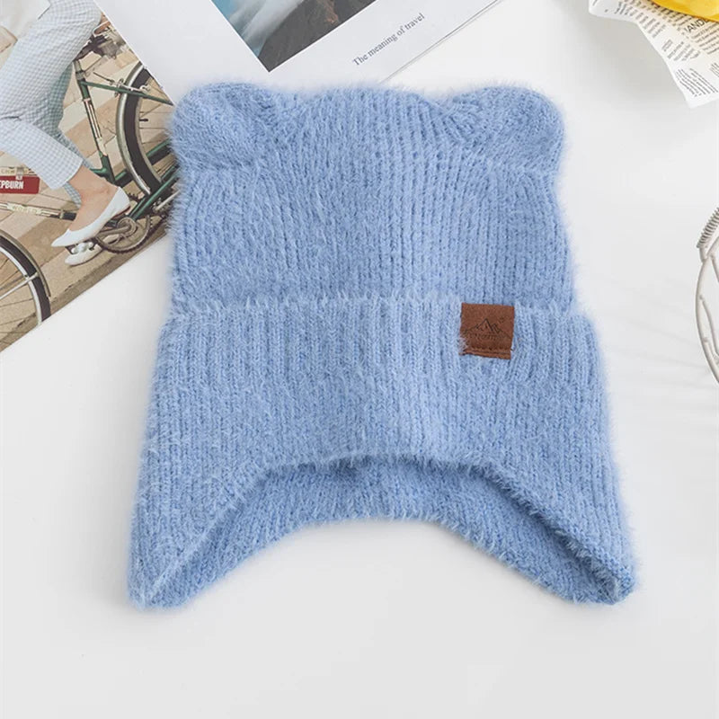 Blue knitted Kawaii beanie with a brown label on a white surface