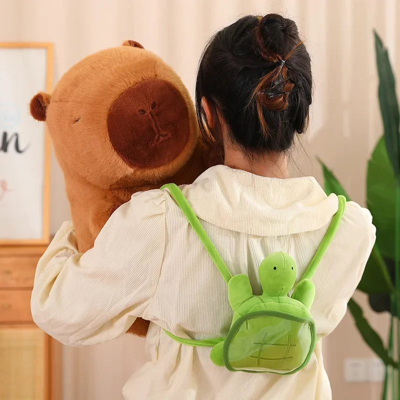 Person wearing a green turtle-shaped backpack with a brown kawaii teddy bear on their shoulder.