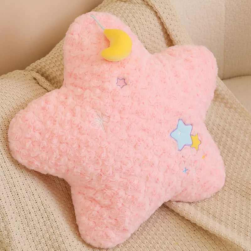 Pink kawaii plush star-shaped pillow with colorful stars on a beige surface