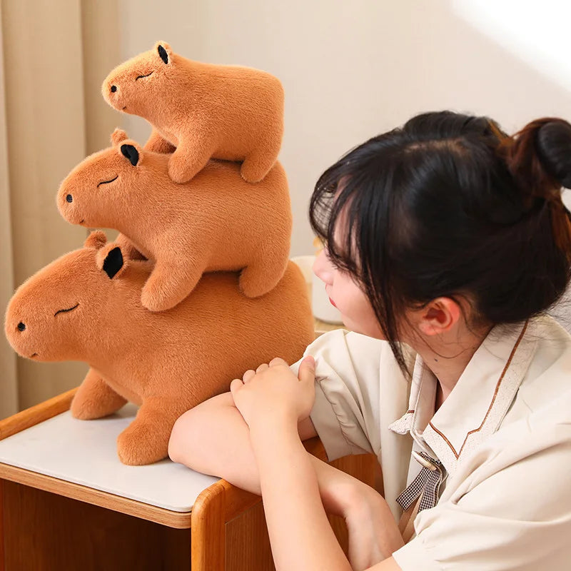 Stack of brown kawaii plush bears with a person sitting next to them on a chair.
