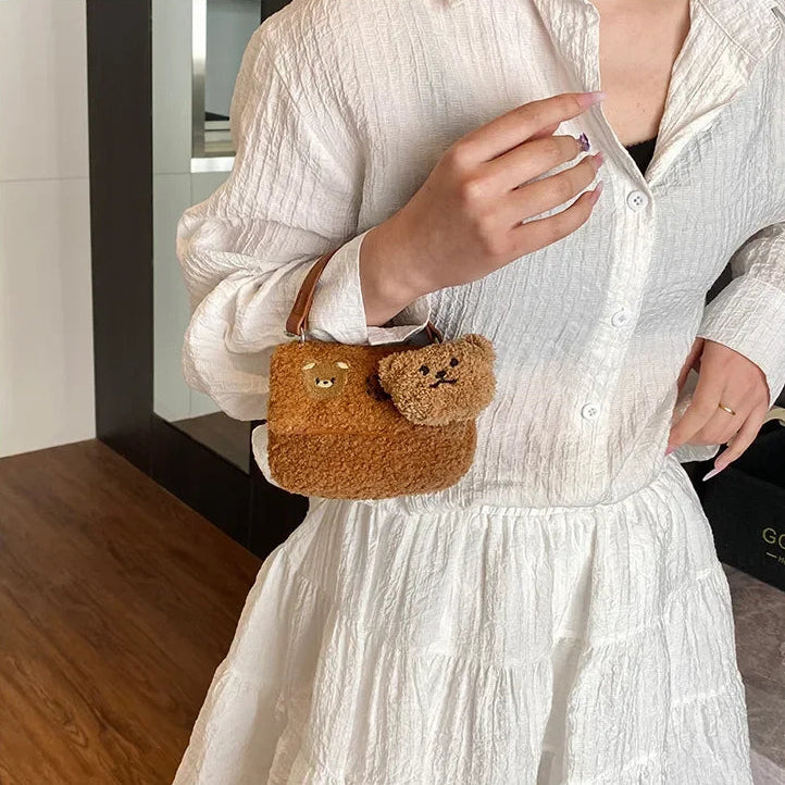 Person wearing a white dress holding a small brown bag with a Kawaii bear design.