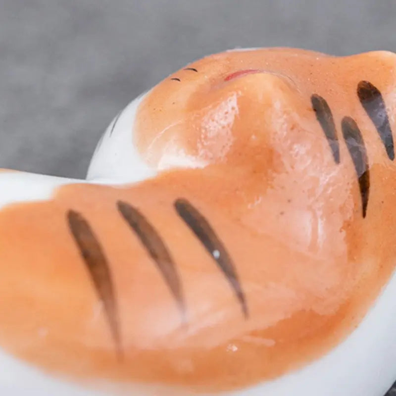 Close-up of a kawaii toy shark with orange body and black stripes on a gray background