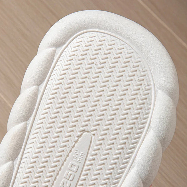Close-up of a white kawaii sneaker sole with brand logo on a wooden floor background