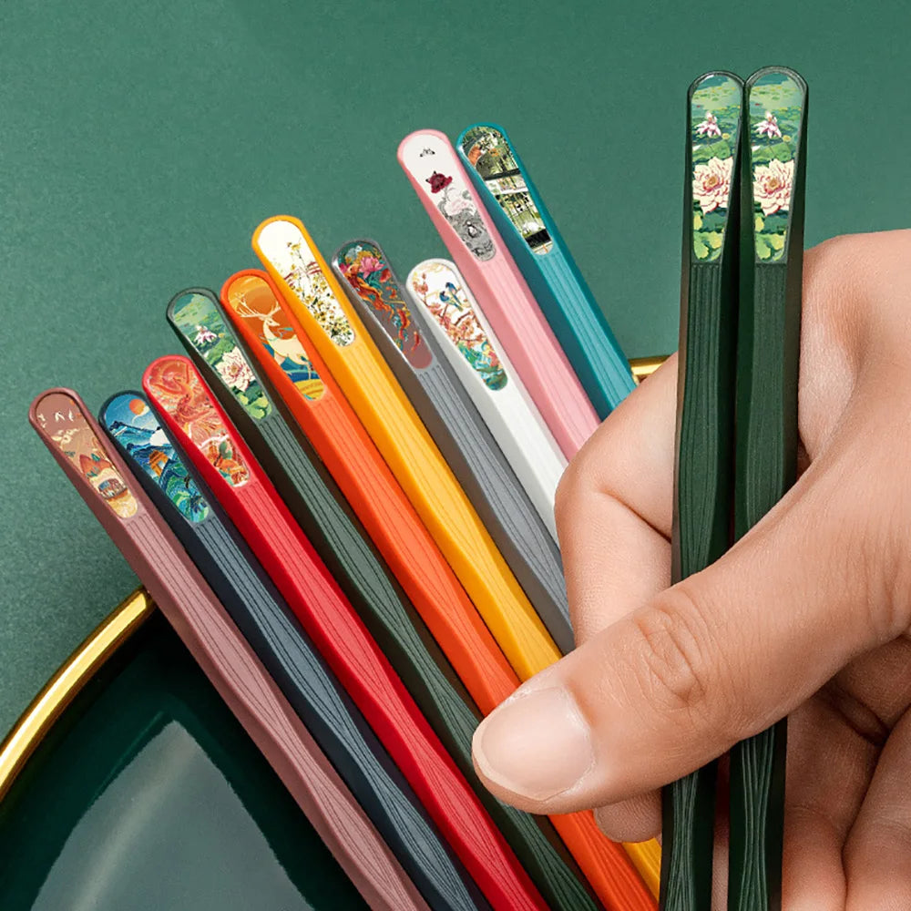 Set of kawaii colorful chopsticks with decorative handles held by a hand against a green background