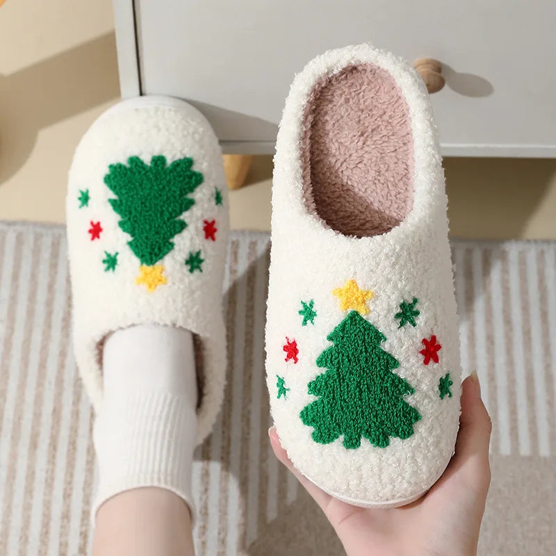 White slippers with Christmas tree kawaii design held by a hand on a neutral background