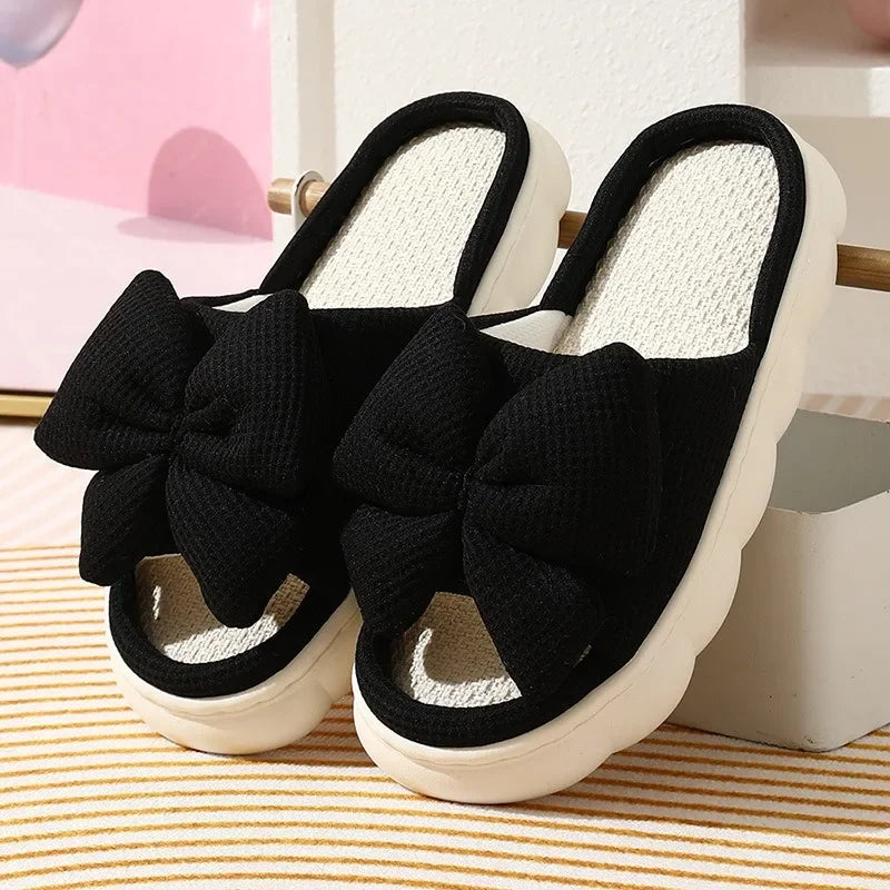 Black slippers with large kawaii bows on a striped surface