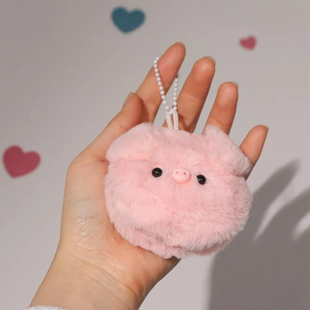 Pink fluffy kawaii keychain held in a hand with a heart-shaped background
