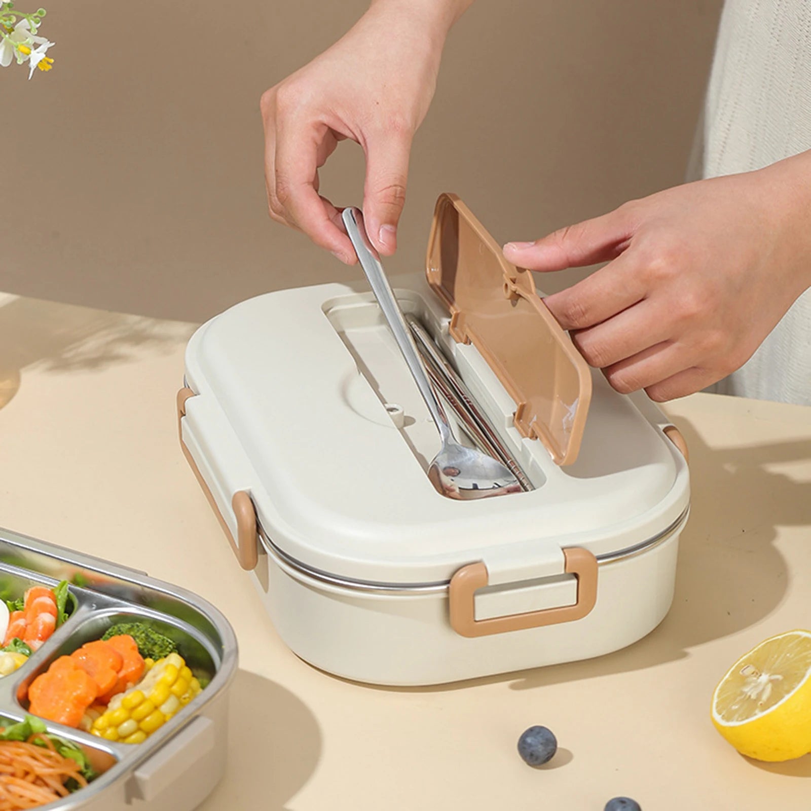 Person opening a kawaii lunch box with compartments and utensils on a table with food.